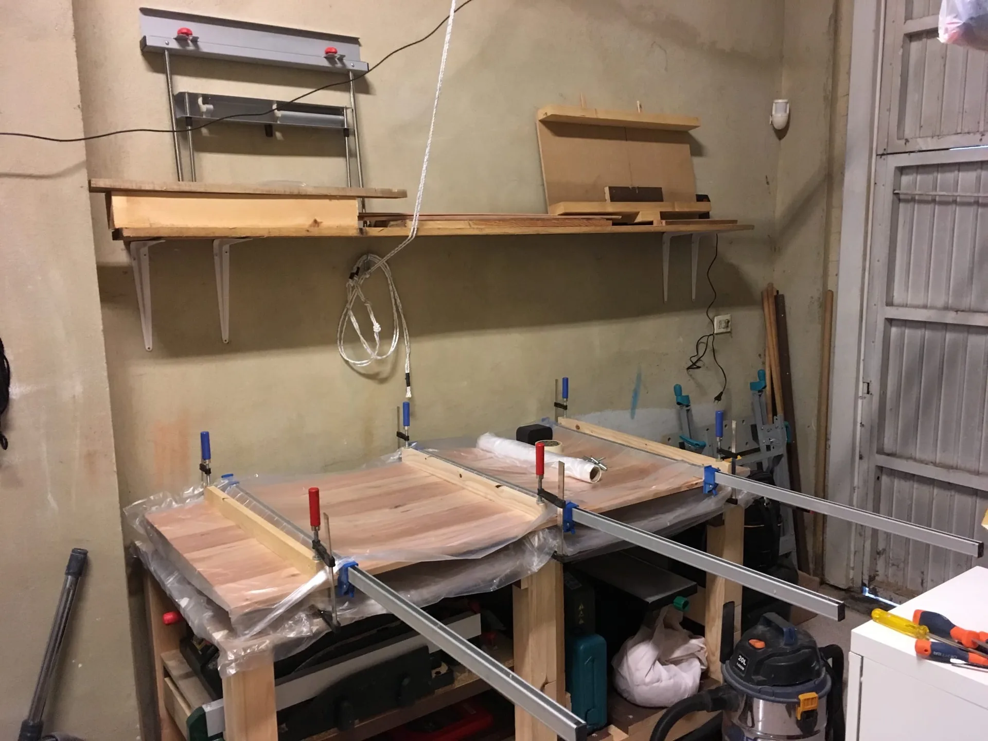 A wooden tabletop held together with clamps during the gluing process {caption: The table top being glued together}